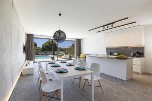 cocina y comedor con mesa blanca y sillas en Momentum Villas, en Ialisos