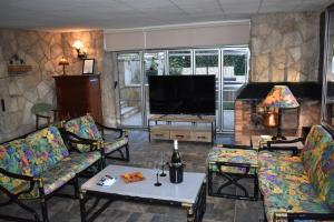 a living room with a television and a couch and chairs at VILLA GARDEN in Tarragona
