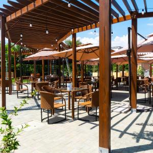 un patio con mesas, sillas y sombrillas en Alpen Park, en Shymkent