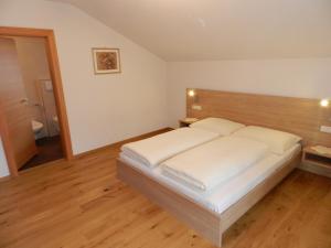 - une chambre avec un grand lit et une tête de lit en bois dans l'établissement Apartments Bachmann, à San Candido