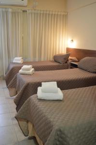 a hotel room with three beds with towels on them at Destino Real Hotel in Buenos Aires