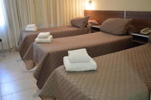 a hotel room with three beds with white towels on them at Destino Real Hotel in Buenos Aires