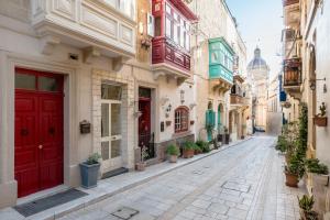 an alley with red doors in an old town at Kharmen A 1565s House with Seaviews in Birgu