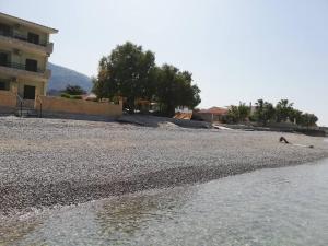 a beach with a building and trees and water at Olea Apartments in Xylokastron