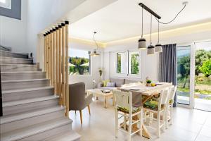 a dining room and kitchen with a table and chairs and a staircase at IRIDA Guesthouse by the Pool in Plakias