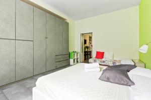 sypialnia z dużym białym łóżkiem i zielonymi ścianami w obiekcie Cenisio & Sempione Cosy Flat w Mediolanie