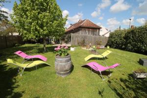 Tres sillas y un barril con flores en un patio en Maison IZARO, en Précy-Saint-Martin