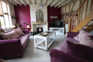 een woonkamer met paarse banken en een open haard bij Maison IZARO in Précy-Saint-Martin