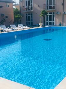 a large blue swimming pool with chairs and a building at Hotel Askar in Alakhadzi