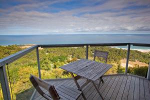 une table en bois et deux chaises assises sur une terrasse dans l'établissement Chris's Beacon Point Restaurant & Villas, à Apollo Bay