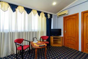 a hotel room with a table and chairs and a television at Sharm Hotel in Adler