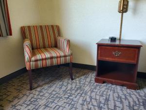 a room with a chair and a dresser and a table at Boarders Inn & Suites by Cobblestone Hotels - Shawano in Shawano