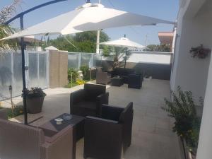 a patio with tables and chairs and an umbrella at B&B villa brezza marina in Sant'Isidoro