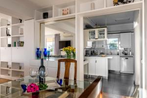 a kitchen with white cabinets and a glass table at Amazing Seafront Apartment Athens Riviera in Athens