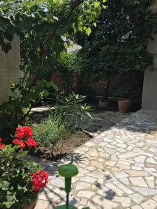 a garden with red flowers and a stone walkway at The ART space in Kavala in Kavála