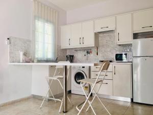 a kitchen with white cabinets and a washer and dryer at Amorgos Gardens in Paphos City