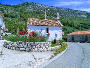 a small house with a stone wall next to a road at Countryside Vacation House VITEZ in Babino Polje