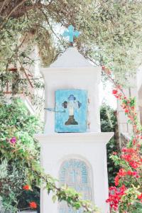 a white clock tower with a cross on top of it at Afroditi Pansion in Agios Nikitas