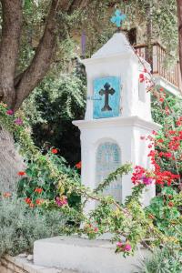 una croce sulla cima di una torre bianca con dei fiori di Afroditi Pansion a Ayios Nikitas