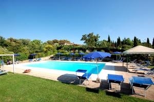 a swimming pool with blue chairs and umbrellas at Antico Borgo Il Cardino in San Gimignano