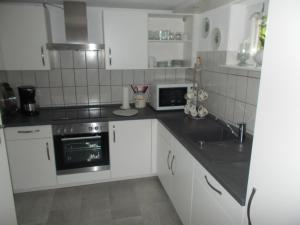 a kitchen with white cabinets and a black counter top at Schlei-Rose in Kappeln