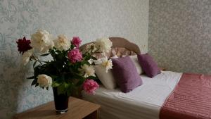 a bedroom with a bed with a vase of flowers on a table at Zhuliany City Hotel in Kyiv