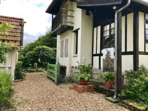uma casa branca e preta com varanda e plantas em l'Atelier au jardin d'Isabelle em Fatouville-Grestain