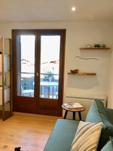 a living room with a couch and a glass door at Appartement cosy et chaleureux à Megève avec vue sur le Mont Blanc in Demi-Quartier