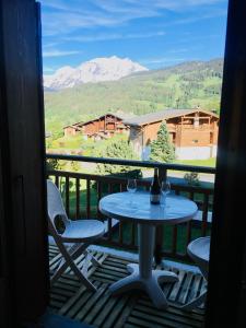 einen Tisch und Stühle auf einem Balkon mit Bergblick in der Unterkunft Appartement cosy et chaleureux à Megève avec vue sur le Mont Blanc in Demi-Quartier