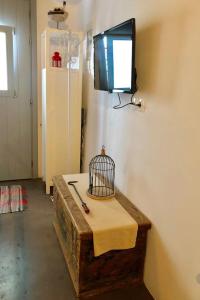 a room with a tv on the wall and a table with a bird cage at Nefeli in Livadi