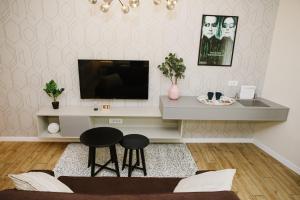uma sala de estar com televisão e dois bancos em Apartman Donner Centar III em Subotica