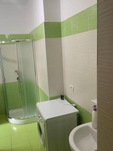 ein grün-weißes Badezimmer mit Waschbecken und Dusche in der Unterkunft Center Apartment in Vlorë