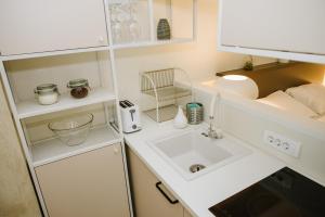 uma pequena cozinha branca com um lavatório e prateleiras em Apartman Donner Centar III em Subotica
