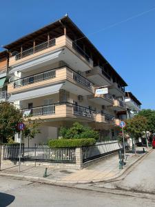 a large white building with balconies on a street at helios apartmenthouse in Olympiaki Akti