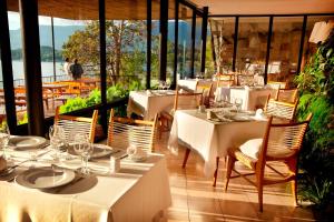 un restaurante con mesas y sillas blancas y ventanas en Hotel Antumalal, en Pucón