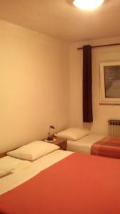 a hotel room with two beds and a window at Apartments Mirjana in Petrcane