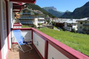 a chair on a balcony with a view of a city at Casa Azzurra in Pozza di Fassa