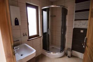 La salle de bains est pourvue d'une douche et d'un lavabo. dans l'établissement Domki Białogóra, à Białogóra