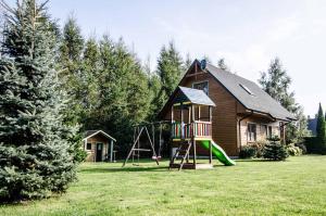 a house with a playground in front of a house at Domki Białogóra in Białogóra