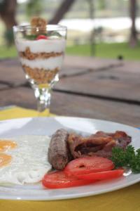 une assiette de nourriture avec des saucisses, des tomates et une boisson dans l'établissement Riverbank Lodge, à Upington