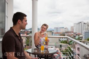 
a man and woman sitting at a table with drinks at Hue Serene Palace Hotel in Hue
