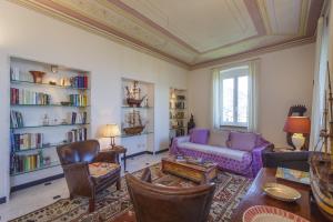ein Wohnzimmer mit einem lila Sofa und Bücherregalen in der Unterkunft VILLA AURORA Relax con Vista Mare e Piscina in Camogli