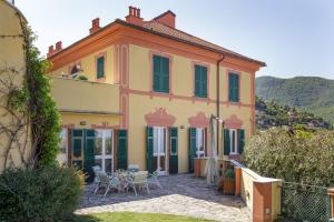 ein großes gelbes Haus mit einem Tisch und Stühlen in der Unterkunft VILLA AURORA Relax con Vista Mare e Piscina in Camogli