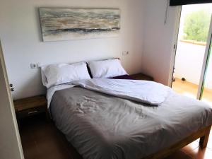 Una cama con sábanas blancas y almohadas en un dormitorio en Apartamentos Habitat Altamar, en Alcossebre