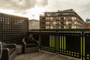 - un balcon avec deux chaises et un bâtiment dans l'établissement Dakota Manchester, à Manchester