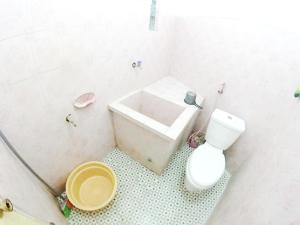 a white bathroom with a toilet and a sink at With Friends Homestay Jogja in Yogyakarta