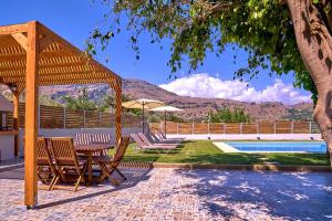 a gazebo with chairs and a table next to a pool at Villa Aelia in Georgioupolis