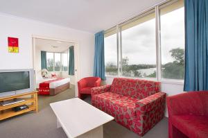 a living room with a red couch and a tv at Chasely Apartment Hotel in Brisbane