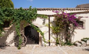 a white house with a gate and purple flowers at Baglio Siciliamo Country House in Noto Marina