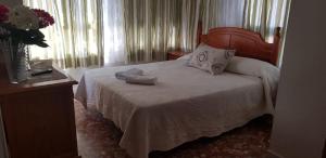 Un dormitorio con una cama y un jarrón con flores. en Hostal San Miguel, en Estepona